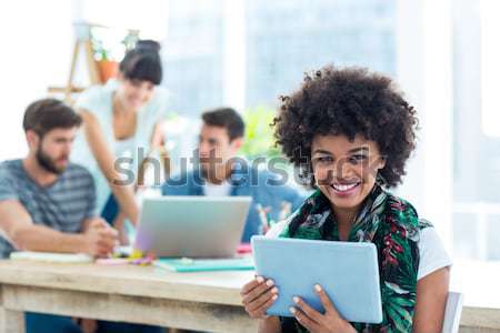 Portrait of smiling waitress with notepad while friends interacting in background Stock photo © wavebreak_media