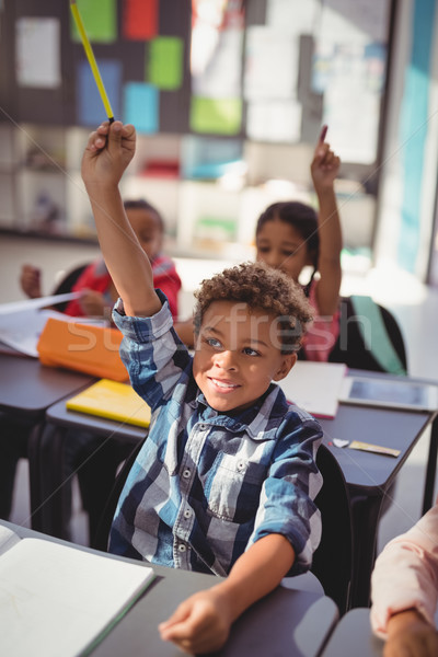 Schoolkids raising their hands in classroom Stock photo © wavebreak_media
