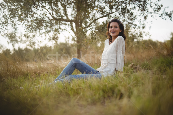 Smiling young woman sitting on grassy field at farm Stock photo © wavebreak_media