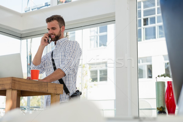 Low angle view businessman talking on mobile phone while standing at desk Stock photo © wavebreak_media