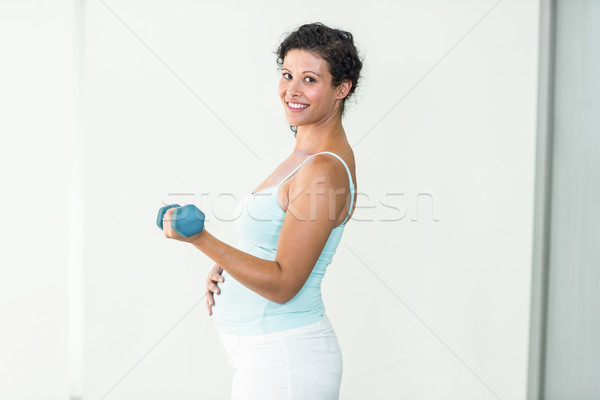 Smiling pregnant woman lifting dumbbells Stock photo © wavebreak_media