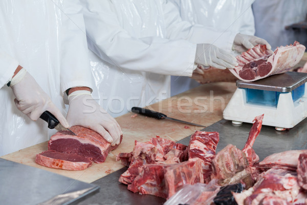 Stock photo: Butchers cutting meat and checking the weight of meat at meat factory