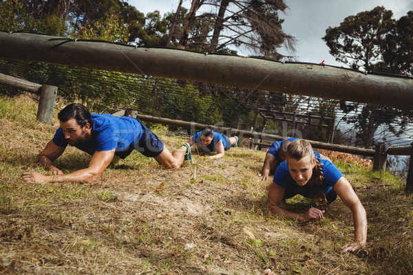 Fit people crawling under the net during obstacle course Stock photo © wavebreak_media