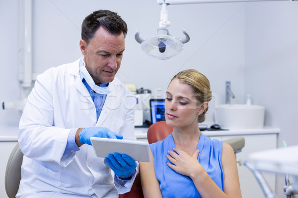 Stock photo: Dentist discussing over digital tablet with female patient