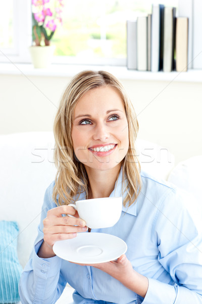 Captivating businesswoman holding a cup sitting on a sofa in the office Stock photo © wavebreak_media
