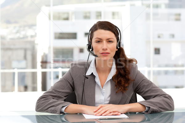 Attractive businesswoman speaking using headset sitting at a table in her office Stock photo © wavebreak_media