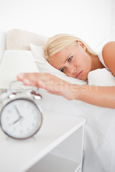 Portrait of an unhappy woman awaken by an alarmclock in her bedroom Stock photo © wavebreak_media