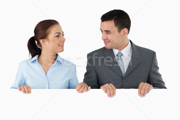 Business partners looking at each other while holding sign together against a white background Stock photo © wavebreak_media