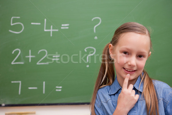 Cute schoolgirl thinking in front of a blackboard Stock photo © wavebreak_media