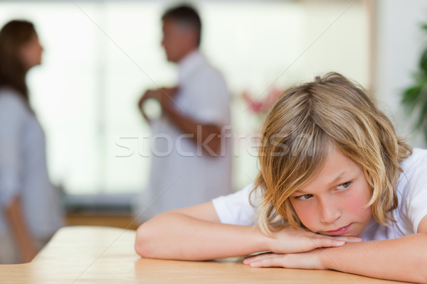 Stock photo: Sad looking boy with his fighting parents behind him