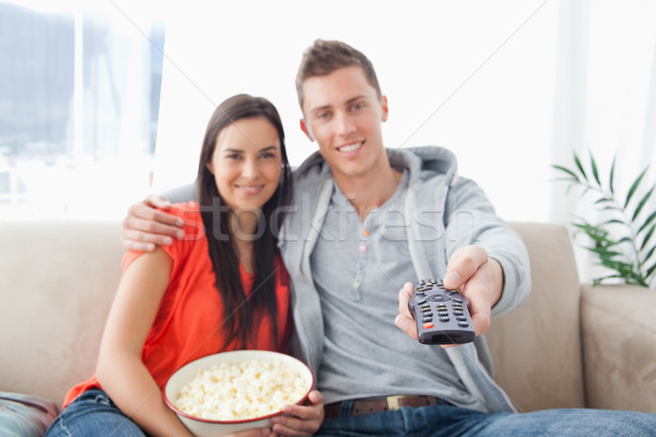 A focused shot on the tv remote on the man's hand as a couple embrace and smile Stock photo © wavebreak_media