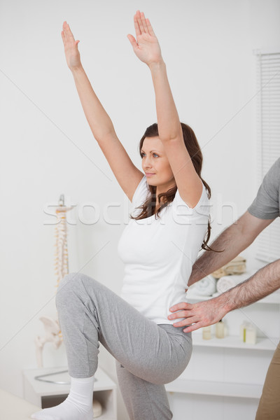 Woman doing exercise while a man is putting his hands on her hips in a room Stock photo © wavebreak_media