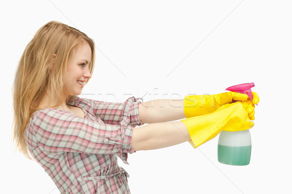 Fair-haired woman holding a spray bottle while smiling against white background Stock photo © wavebreak_media