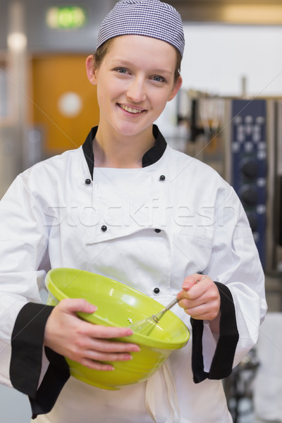 Stock photo: Female baker smiling and mixing in the kitchen