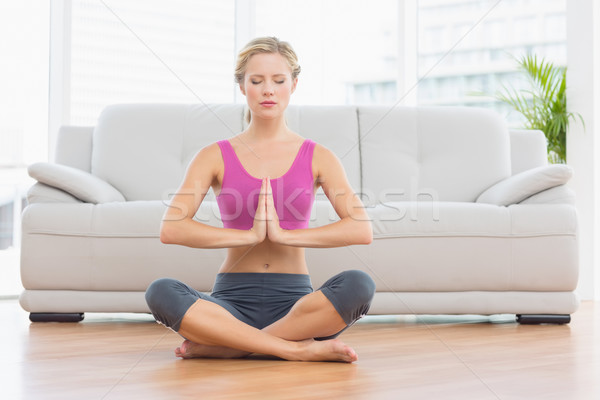 Stock photo: Calm blonde sitting in lotus pose with hands together