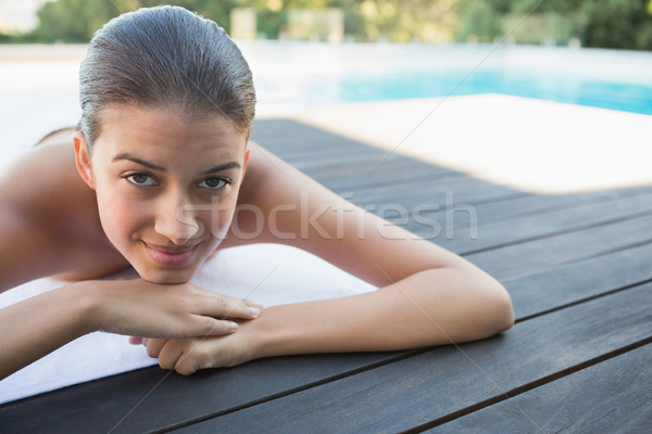Smiling brunette lying on a towel poolside Stock photo © wavebreak_media