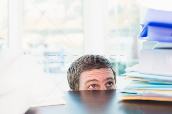 Scared businessman peeking over desk  Stock photo © wavebreak_media