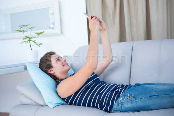 Pretty woman lying on couch taking a selfie  Stock photo © wavebreak_media