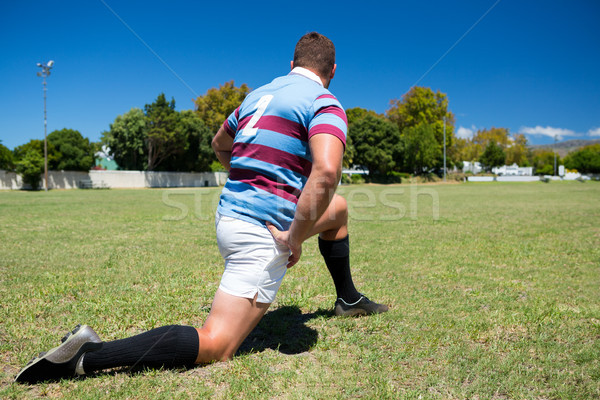 Rear view of rugby player exercising while kneeling on grassy field Stock photo © wavebreak_media