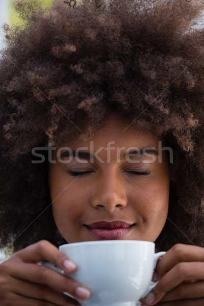 Stock photo: Smiling woman with frizzy hair smelling coffee