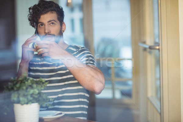 Man sipping coffee while talking on cellphone at cafe Stock photo © wavebreak_media