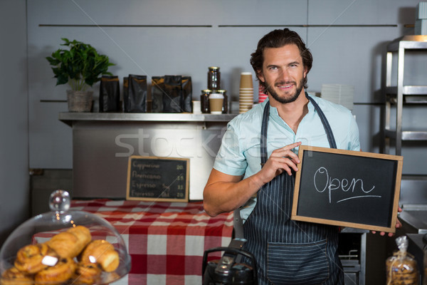 Stock photo: Male staff holding a board with open sign