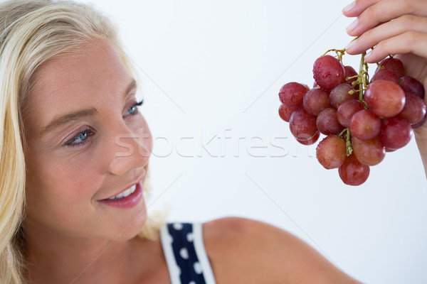 Beautiful woman looking at bunch of red grapes Stock photo © wavebreak_media