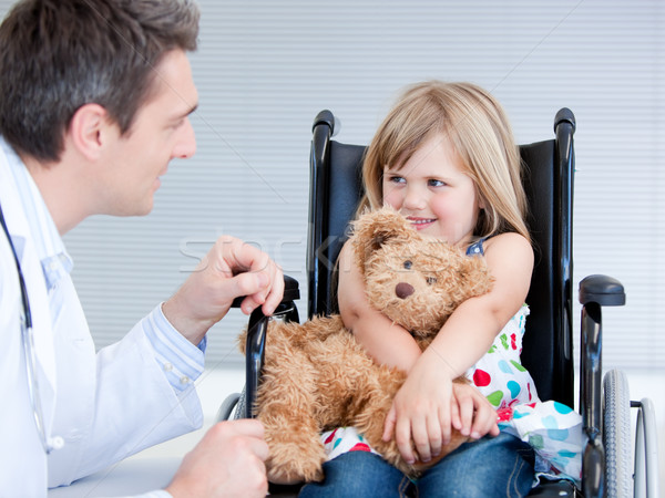Stock photo: Smiling little girl sitting on the wheelchair lokking at the doctor
