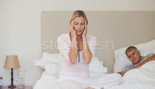 Stock photo: Woman having a headache while her husband is sleeping