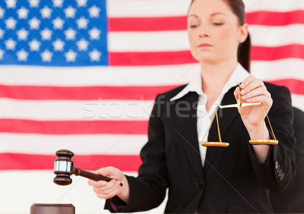 Close up of a young judge knocking a gavel and holding scales of justice with an American flag in th Stock photo © wavebreak_media