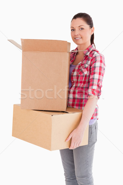 Stock photo: Attractive woman holding cardboard boxes while standing against a white background