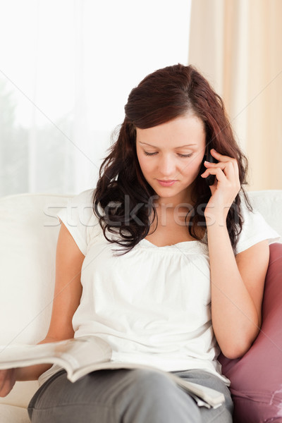 Young woman with a magazine calling someone in her livingroom Stock photo © wavebreak_media