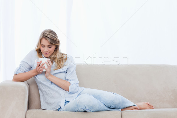 Stock photo: A young woman is smelling a cup of coffee that she is holding