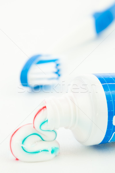 Blue toothpaste tube next to a toothbrush against white background Stock photo © wavebreak_media