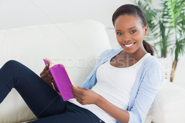 Black woman sitting on a sofa while holding a book in a living room Stock photo © wavebreak_media