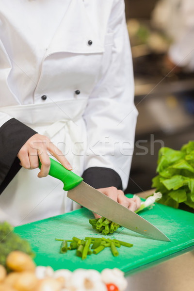 Chef slicing up scallions on chopping board in kitchen Stock photo © wavebreak_media