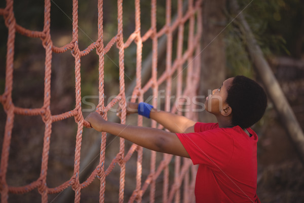 Determined boy climbing a net during obstacle course Stock photo © wavebreak_media