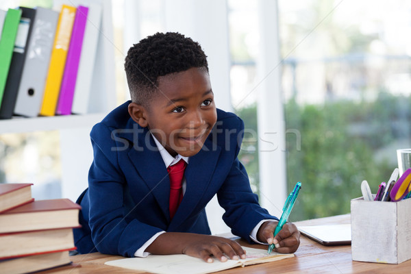 Stock photo: Smiling businessman looking away while writing on book