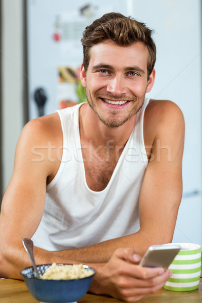 Przystojny młody człowiek telefonu komórkowego śniadanie tabeli portret Zdjęcia stock © wavebreak_media