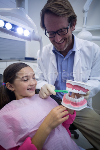 Dentist showing young patient how to brush teeth Stock photo © wavebreak_media