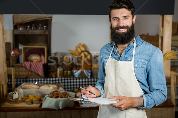 Salesman writing on clipboard at counter in grocery shop Stock photo © wavebreak_media