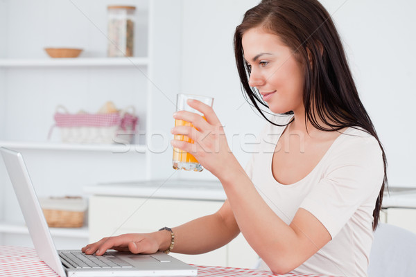 женщину используя ноутбук питьевой сока кухне Сток-фото © wavebreak_media