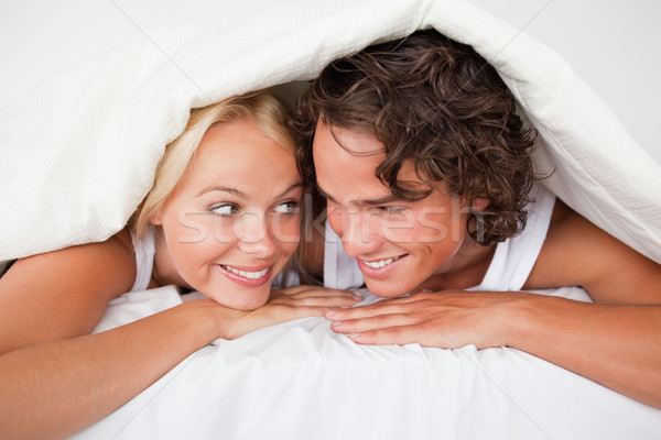 Couple under a duvet with a knowing smile in a bed Stock photo © wavebreak_media