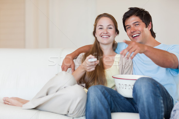 Laughing couple watching television while eating popcorn in their living room Stock photo © wavebreak_media