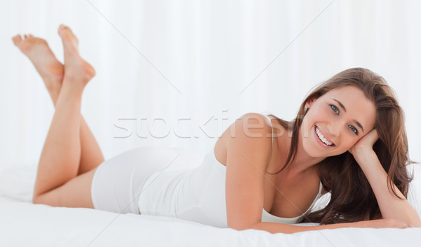 A woman lying in bed with her head in her hand, smiling as she looks forward, with her legs raised u Stock photo © wavebreak_media