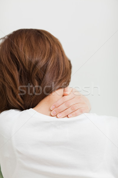 Brown-haired woman massaging her painful neck in a room Stock photo © wavebreak_media