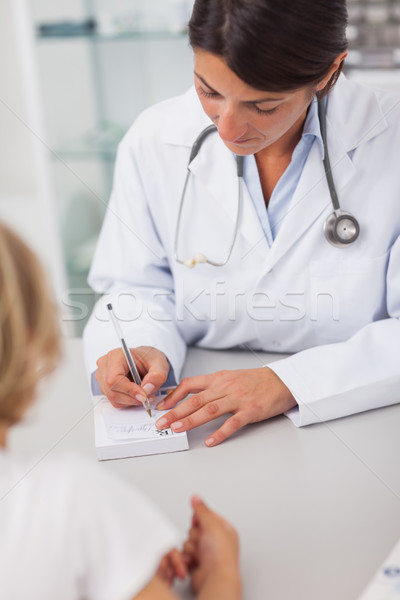 Stock photo: Doctor writing on a prescription note in medical office