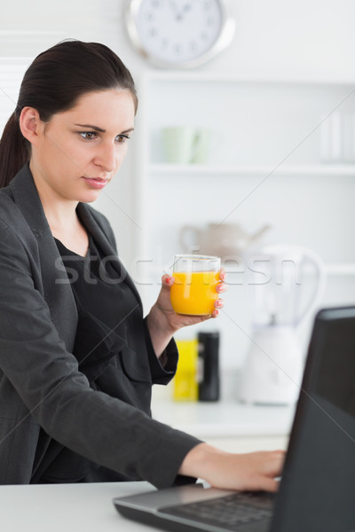 Mulher usando laptop suco vidro cozinha Foto stock © wavebreak_media