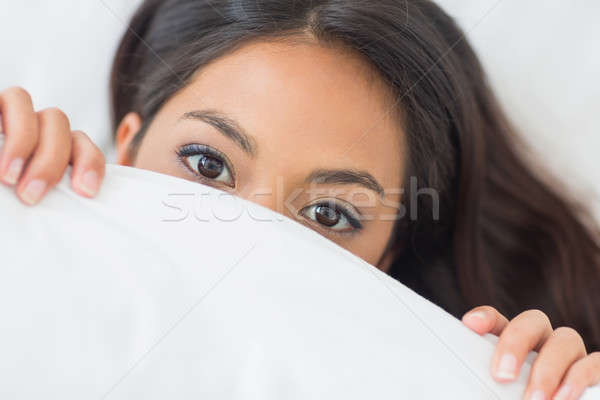 Pretty girl peeking from under the duvet Stock photo © wavebreak_media