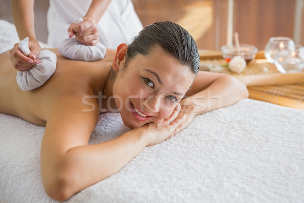 Content brunette enjoying a herbal compress massage Stock photo © wavebreak_media